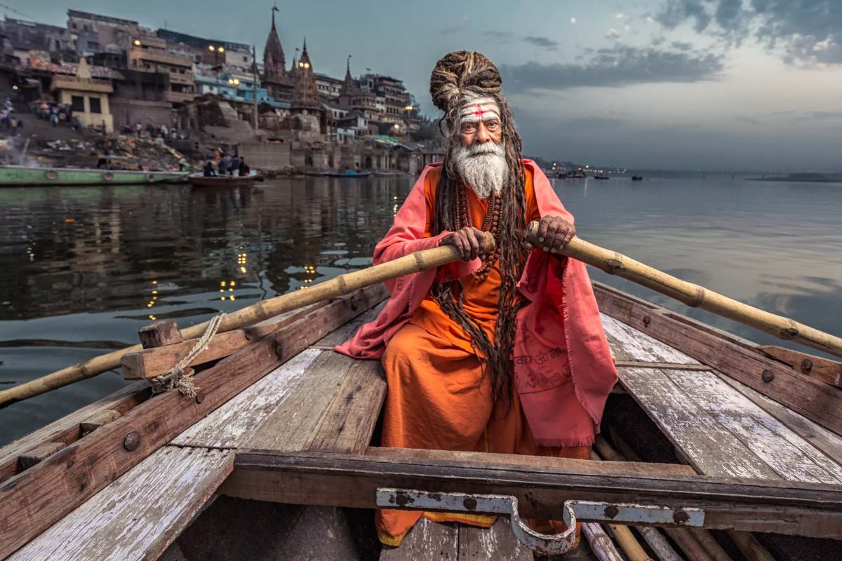 indian man rowing a boat on the ganges river, in varanasi