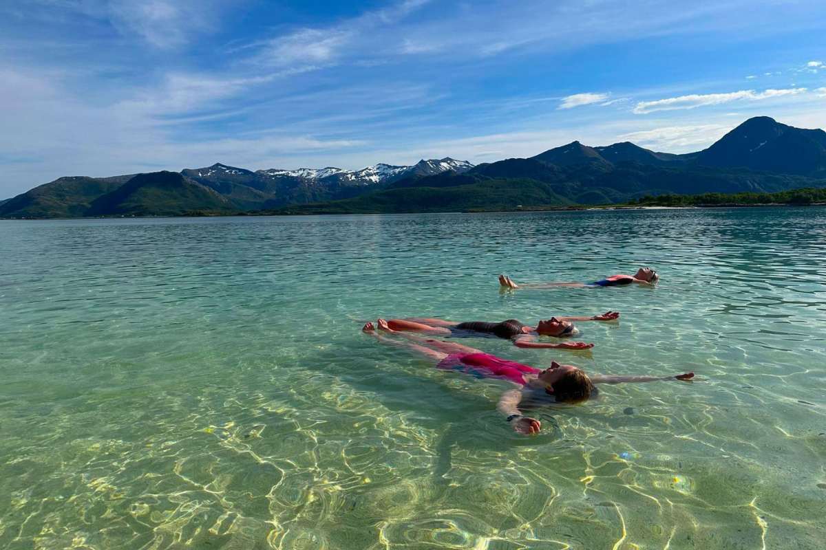 women wild swimming in crystal clear fjords of senja, norway