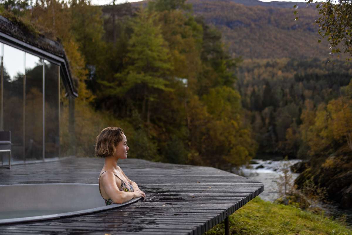 woman sitting in hot tub looking at views of fjords and mountain on west norway yoga retreat